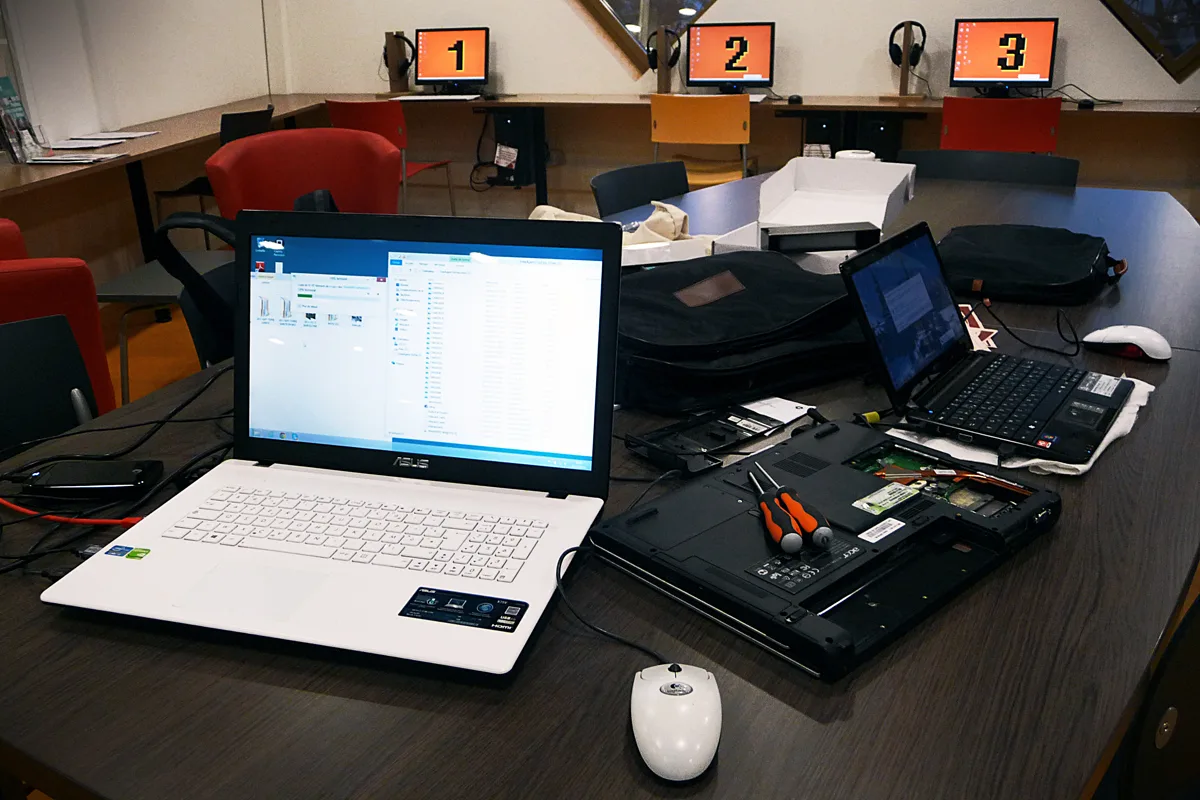 Laptops, tools and replacement parts on a computer-repair table.