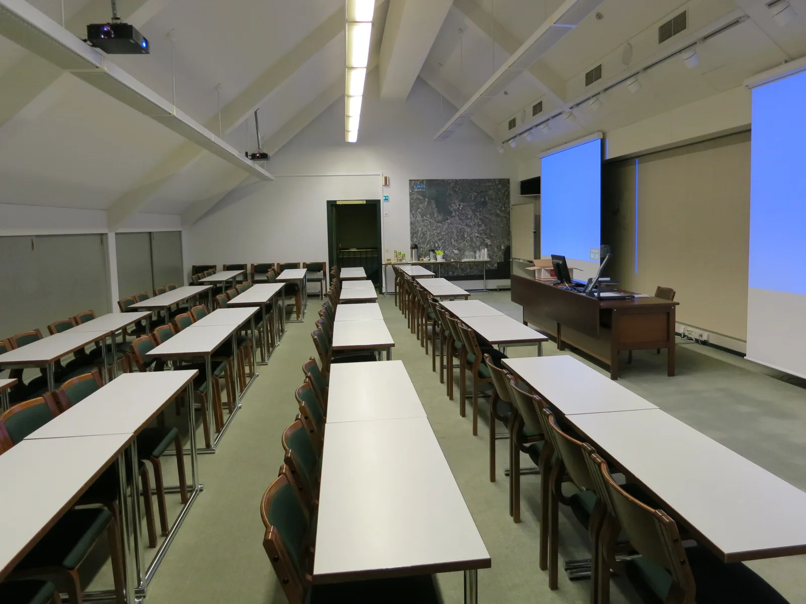 Rows of desks and chairs face screens in the attic meeting room of Lahti City Hall.