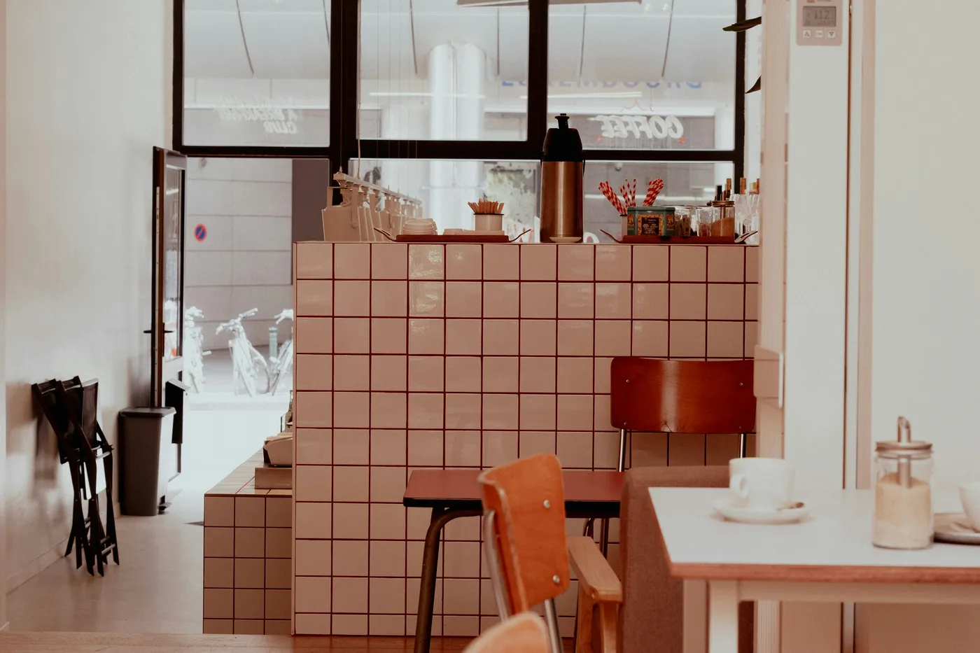 Empty tables, wooden chairs and a pink-tiled counter in a Brussels café.