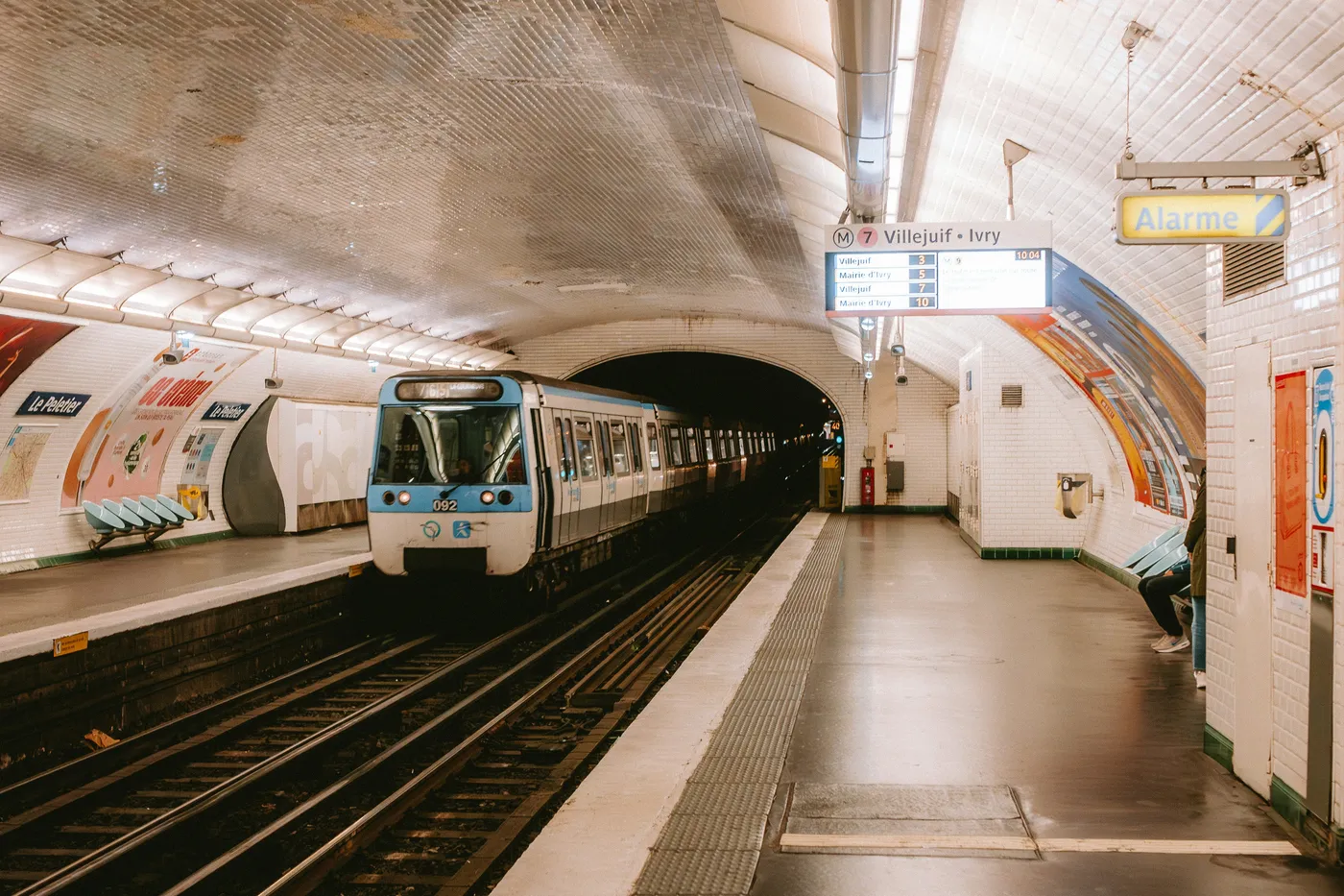 A métro train beside the tiled platforms at Le Peletier station in Paris.
