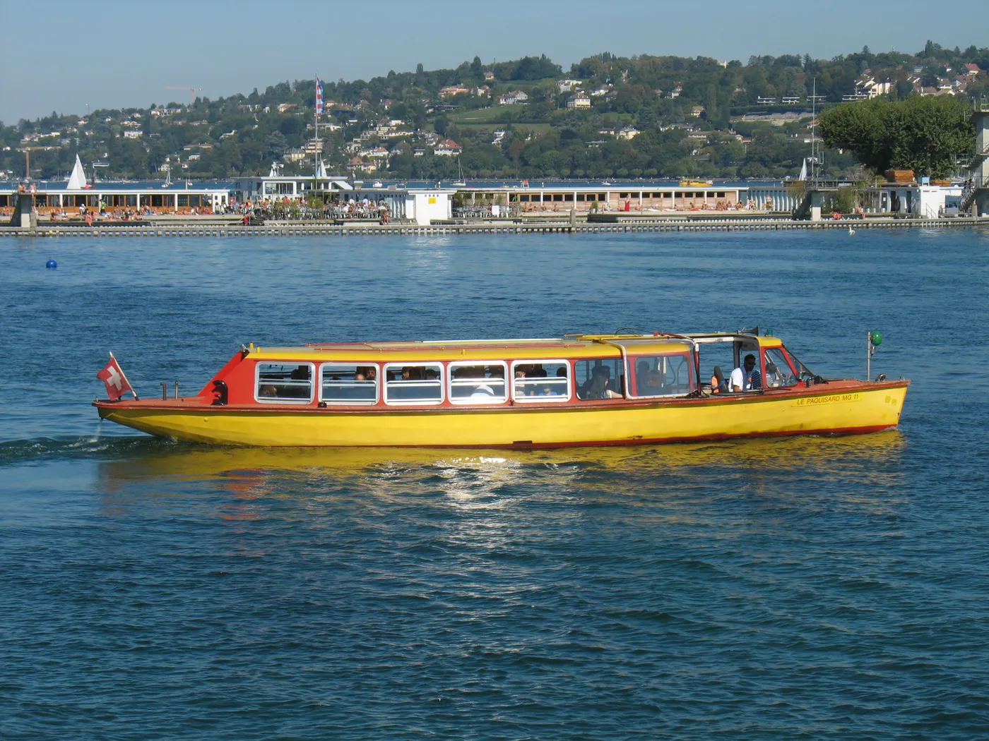 A yellow and red Mouette passenger ferry crossing Geneva’s harbour.